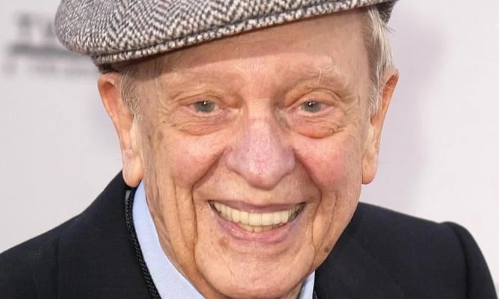 An elderly man in a checkered flat cap smiles warmly-don knotts net worth