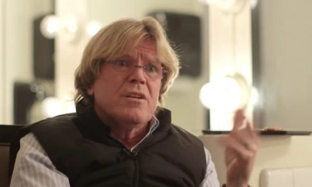 A person with shoulder-length blonde hair and glasses-peter noone net worth