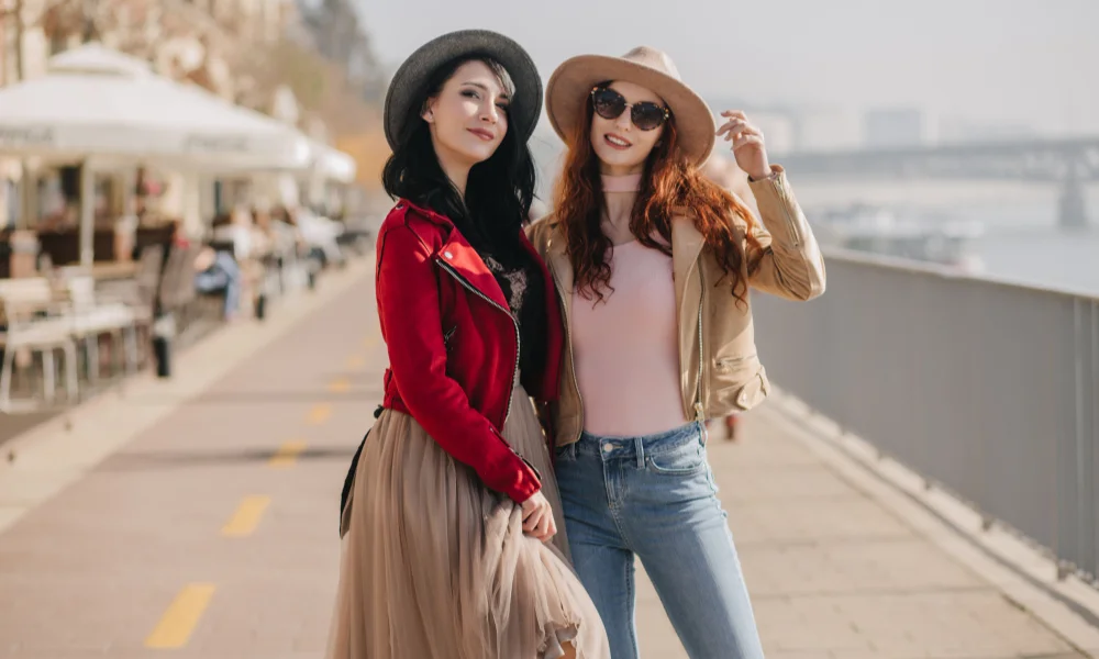 Two stylish women pose confidently on a sunny promenade-trending outfits for women