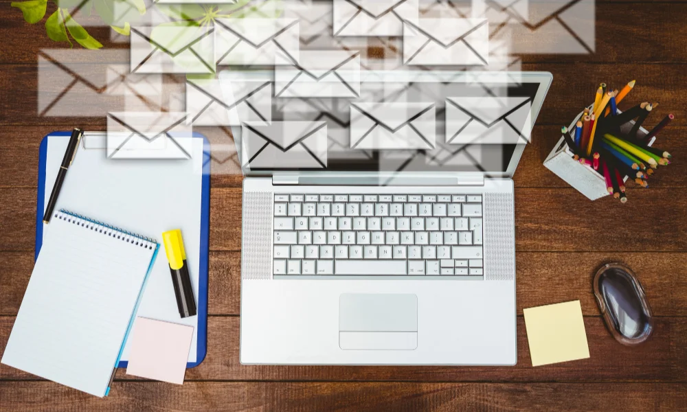 laptop on a wooden desk surrounded by a notepad-email marketing news 2025
