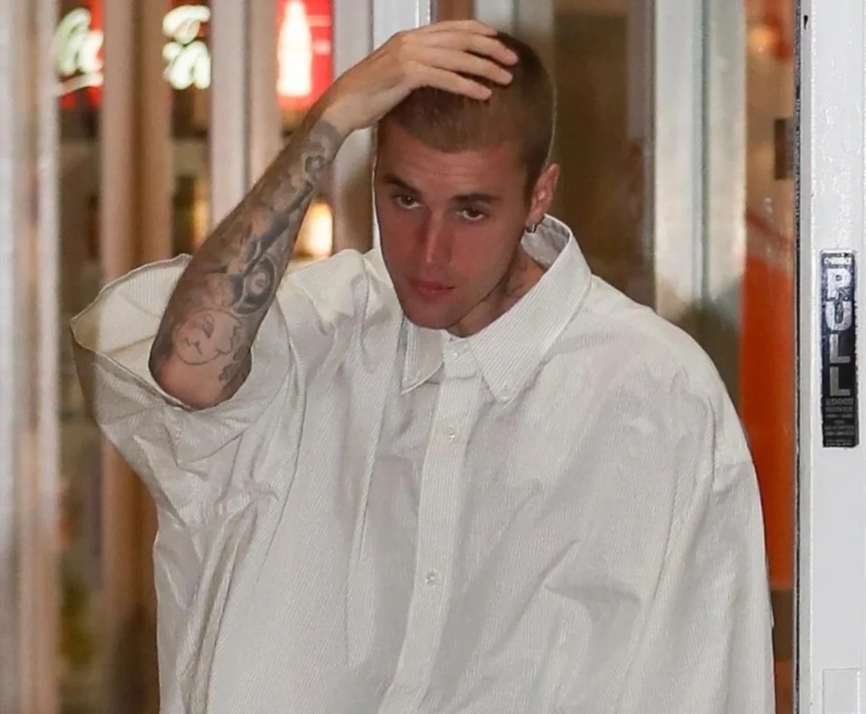 Justin Bieber wearing a white oversized shirt, reflecting his mature music career and Justin Bieber early life story on Mariano Iduba.