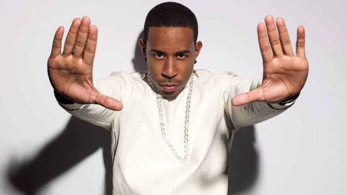 Man in a white shirt with a chain necklace poses confidently