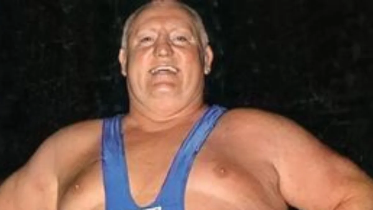 muscular man wearing a blue wrestling singlet stands