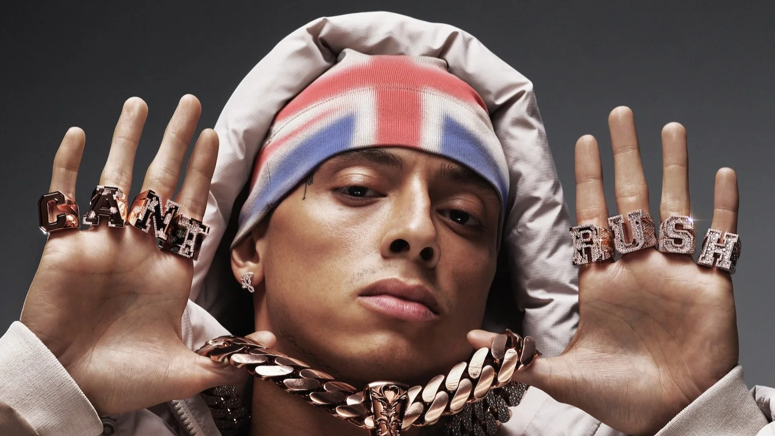 A rapper Central Cee wearing a Union Jack headband and gold chains, illustrating how Central Cee became famous and his success story.