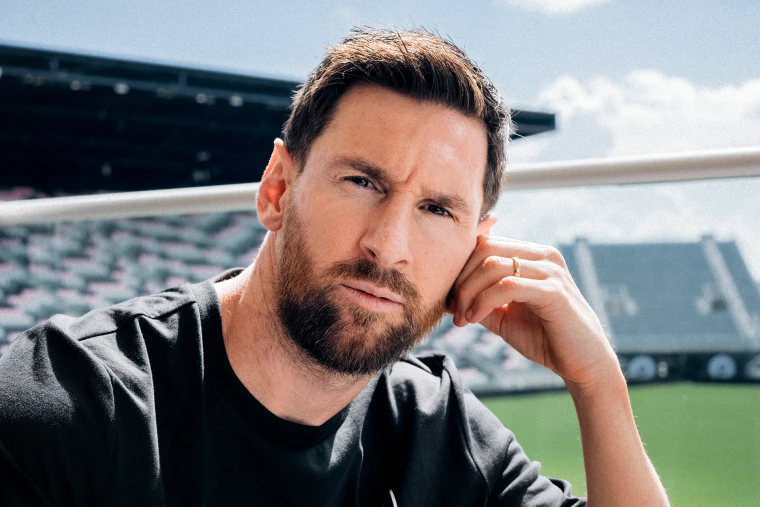 Close-up portrait of Lionel Messi looking thoughtfully at the camera at a stadium.